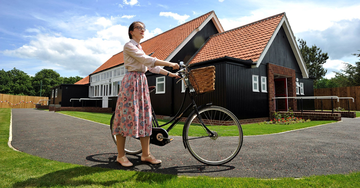 woman with bicycle stood outside the 1950s welfare hall at Beamish Museum